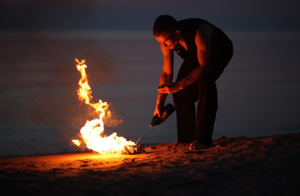photograph of a man adding fuel to a fire